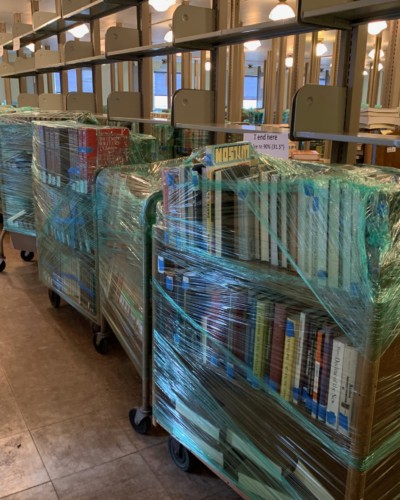 Wrapped books delivered from Milne to Fraser, lined up for unpacking and sorting, Spring 2021 Wrapped books delivered from Milne to Fraser, lined up for unpacking and sorting