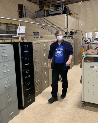 Sullivan among long line of book trucks and filing cabinets in Schrader Hall, Spring 2021 Sullivan among long line of book trucks and filing cabinets in Schrader Hall, Spring 2021