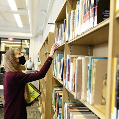 Patron selecting book in new Fraser Hall Library, Spring 2021 Patron selecting book in new Fraser Hall Library, Spring 2021